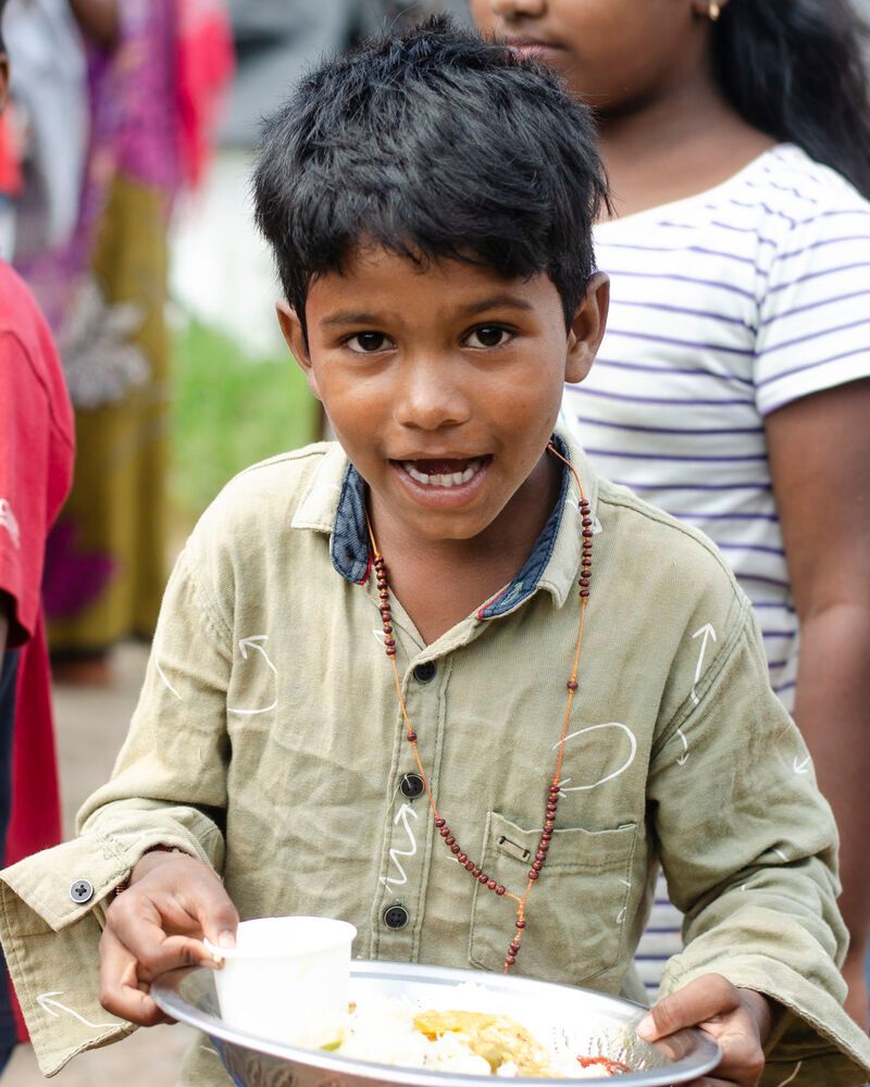 A smiling boy holding his plate of food at the September 2022 food distribution