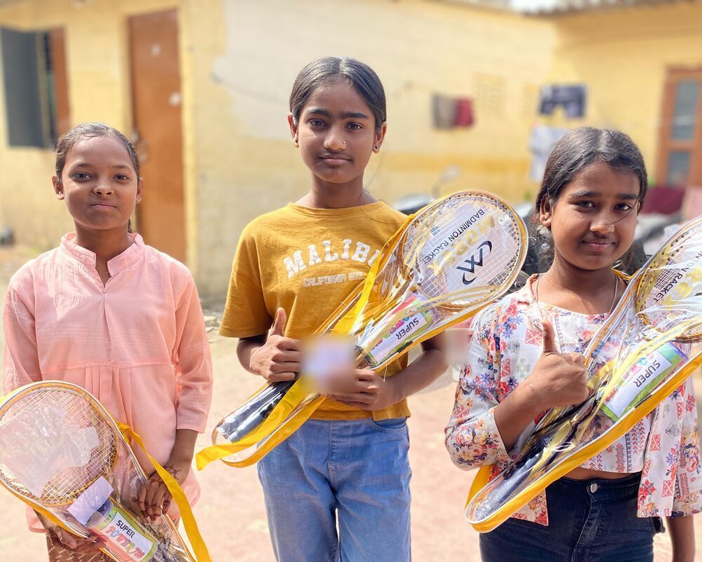 Three girls with the badminton sets they got at Gift a Smile