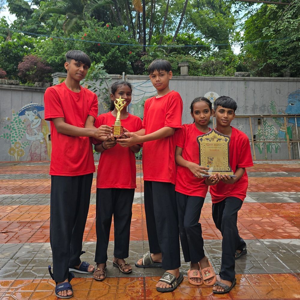 Children in red T-shirts holding their dance trophies